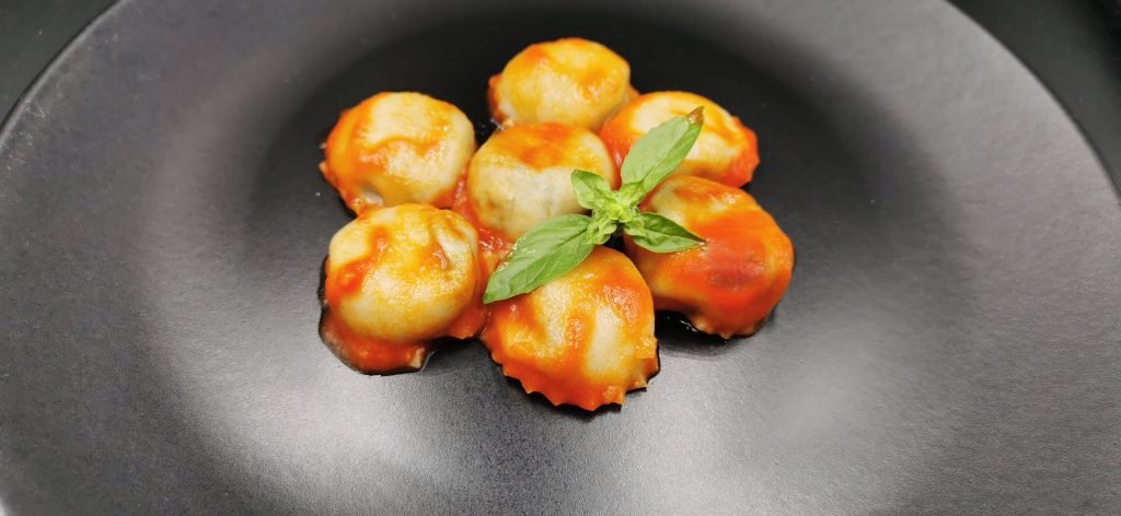 Pasta fresca rellena servida caliente con un hilo de aceite brillante para Ravioles de Espinacas