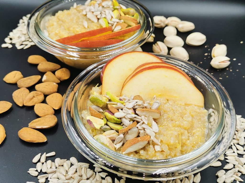 Tazón de granos cocidos con rodajas de manzana fresca y pistachos verdes picados para Porridge de Quinoa
