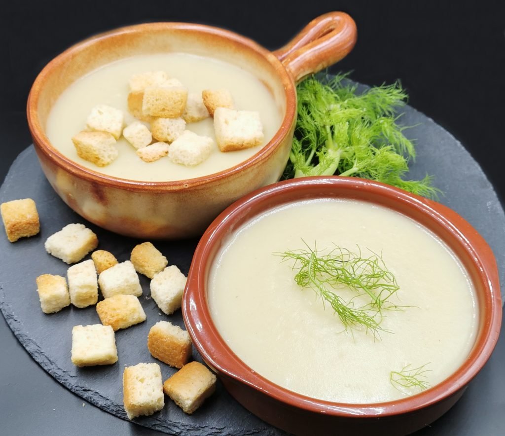 Sopa espesa y suave de tono claro decorada con hojas verdes frescas para Crema de Hinojo