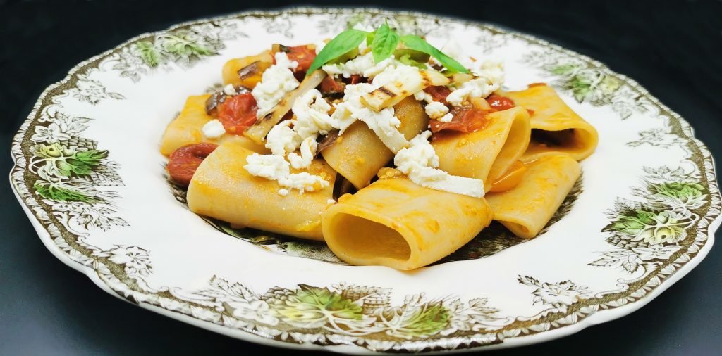 Pasta con salsa de tomate y trozos oscuros de vegetal coronada con queso para Pasta con Berenjena
