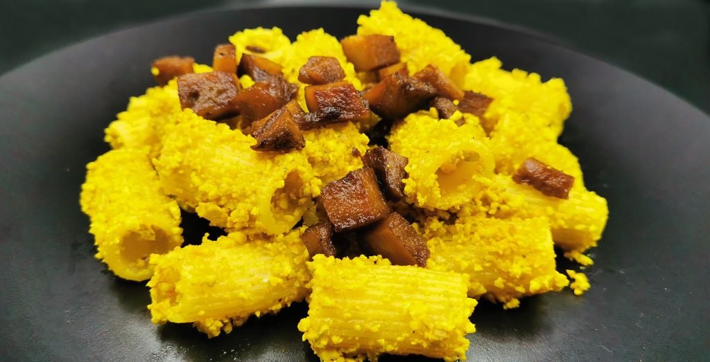 Rigatoni bañados en salsa cremosa amarilla con trozos de seitán dorado para Pasta Carbonara
