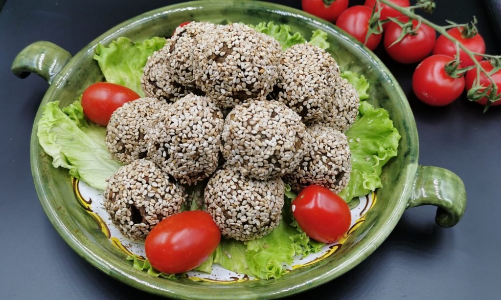 Bolitas horneadas de tono oscuro cubiertas de semillas de sésamo tostadas para Albóndigas de Berenjena