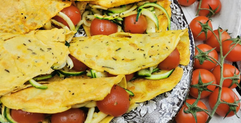 Discos finos y dorados servidos con espaguetis de vegetales verdes para Tortillas de Garbanzo