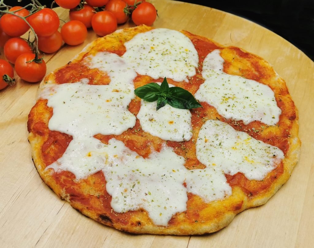 Masa fina con bordes inflados cubierta de salsa roja, queso fundido y albahaca para Pizza Margarita