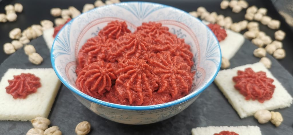 Crema vibrante de color fucsia y textura suave servida con aceite para Hummus de Remolacha