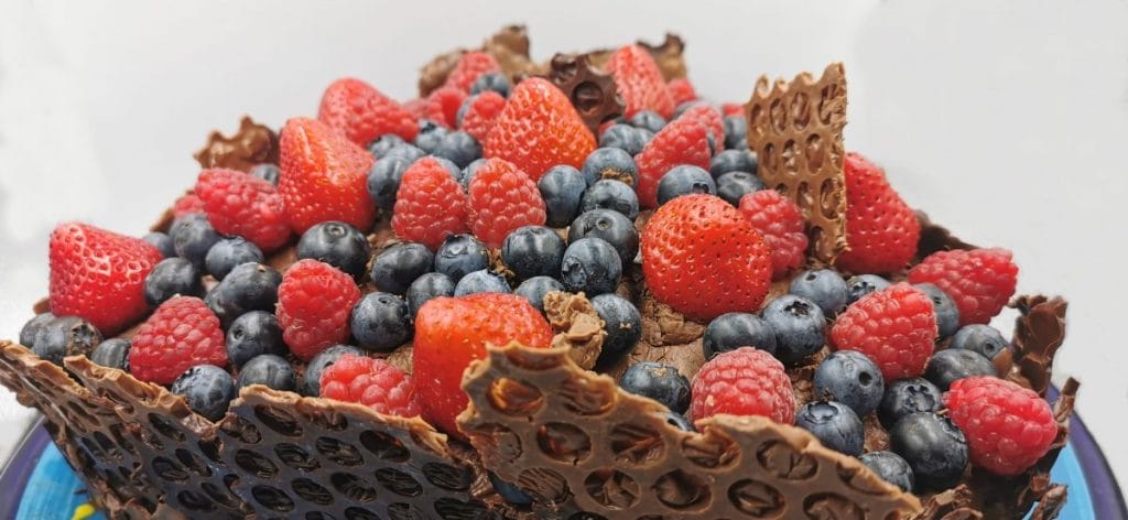Tarta alta en capas con borde de chocolate texturizado y frutos rojos frescos para Pastel de Chocolate y Fresas