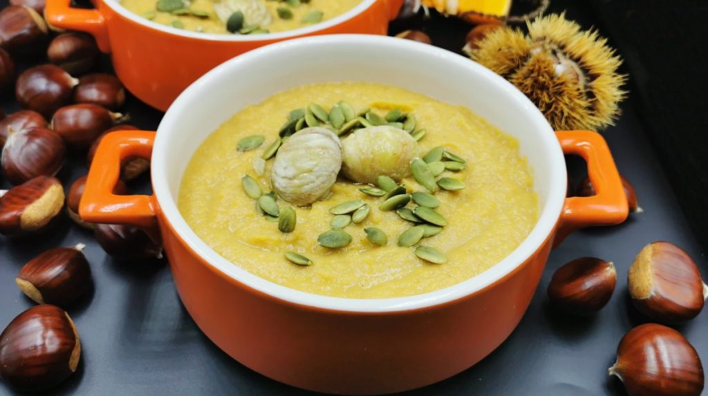Sopa cremosa de tono naranja suave decorada con castañas enteras y especias para Crema de Ayote y Castañas