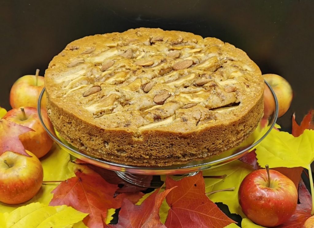 Bizcocho húmedo y dorado cubierto con láminas de fruta y frutos secos para Pastel de Manzana