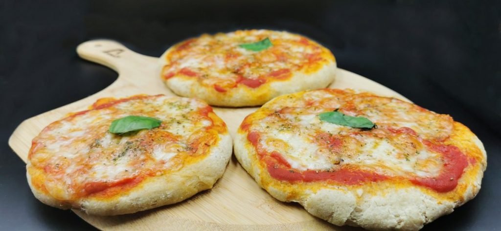 Pequeñas pizzas redondas con salsa roja, mozzarella fundida y albahaca fresca para Pizzitas Merenderas