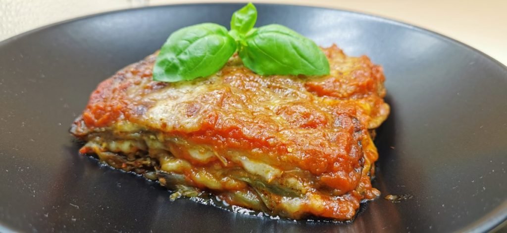 Cazuela gratinada con capas de vegetales, salsa roja y queso fundido dorado para Parmigiana de Berenjena