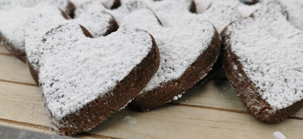 Galletas oscuras en forma de corazón con superficie agrietada y azúcar glas para Galletas de Almendras