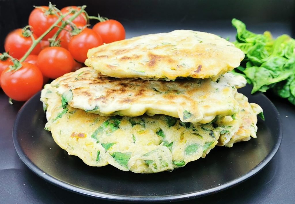 Tortitas esponjosas con tono verde y trocitos de verduras doradas en sartén para Pancakes Salados de Espinacas