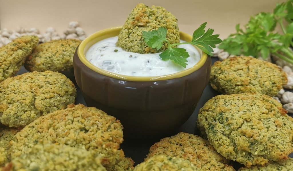 Croquetas doradas y crujientes con interior suave y salsa blanca cremosa para Falafel de garbanzos al horno
