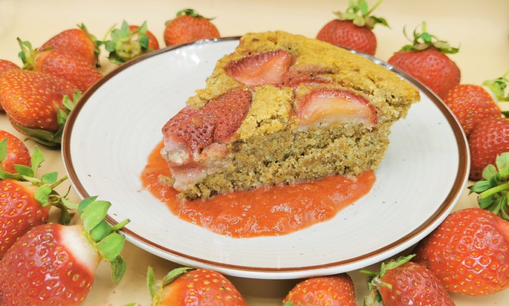 Bizcocho alto y esponjoso con trozos de fruta roja horneada en la superficie para Pastel de Fresas Vegano