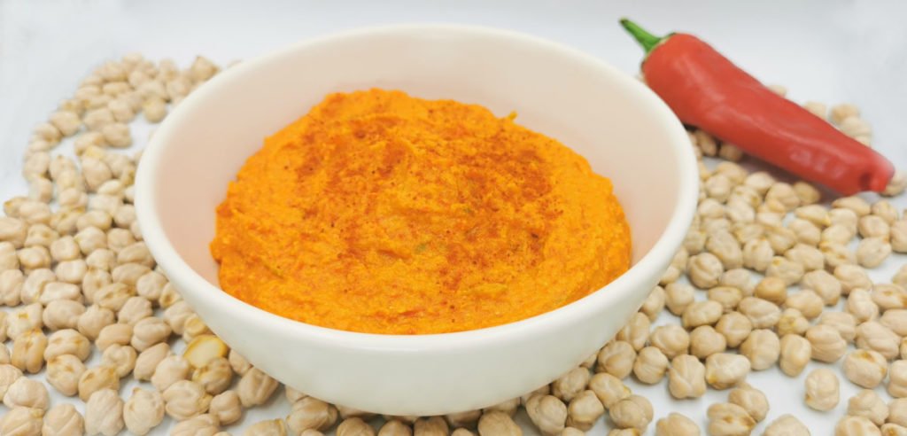 Crema untable de color anaranjado suave con textura sedosa y pimentón para Hummus de Chile Dulce casero
