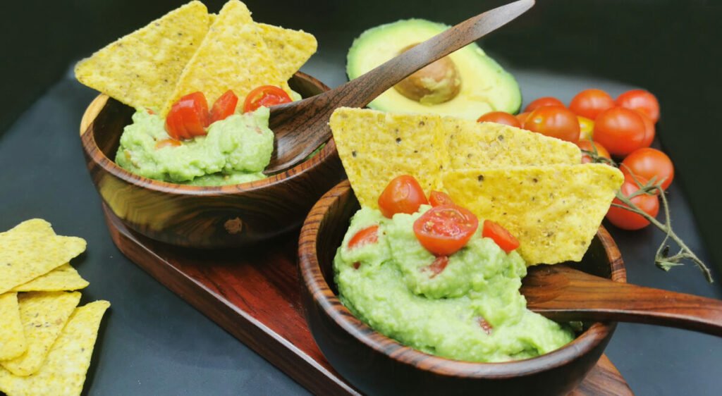 Dip verde y cremoso de aguacate machacado con trozos de tomate y cebolla para Guacamole fresco
