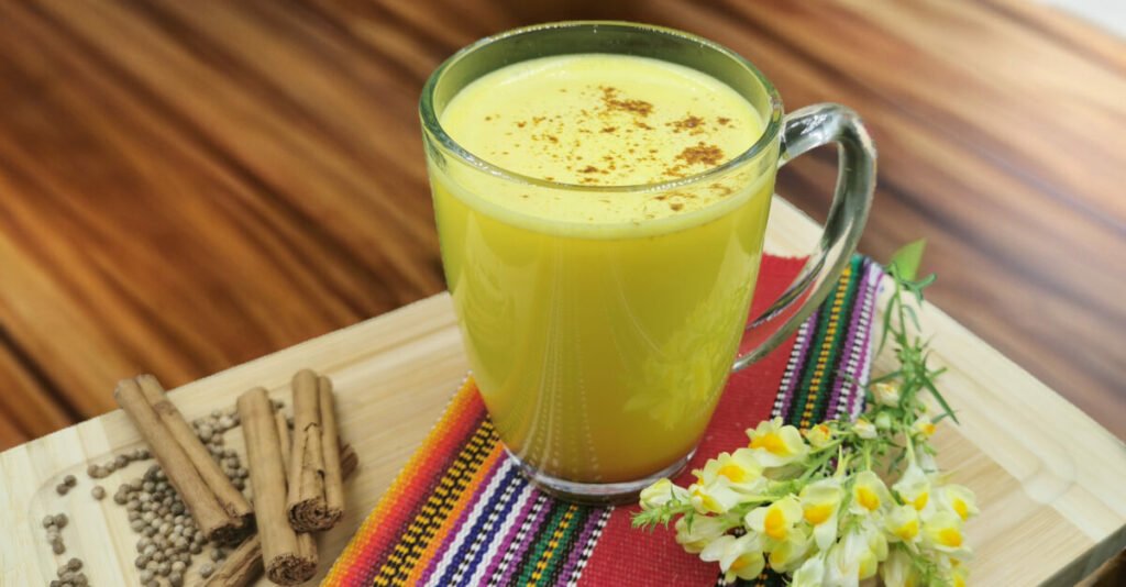 Bebida caliente de color amarillo intenso con espuma y canela para Leche Dorada reconfortante