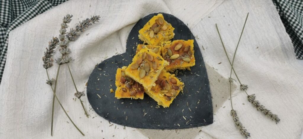 Pan plano y esponjoso de color anaranjado con aceite de oliva y romero fresco para Focaccia de Ayote