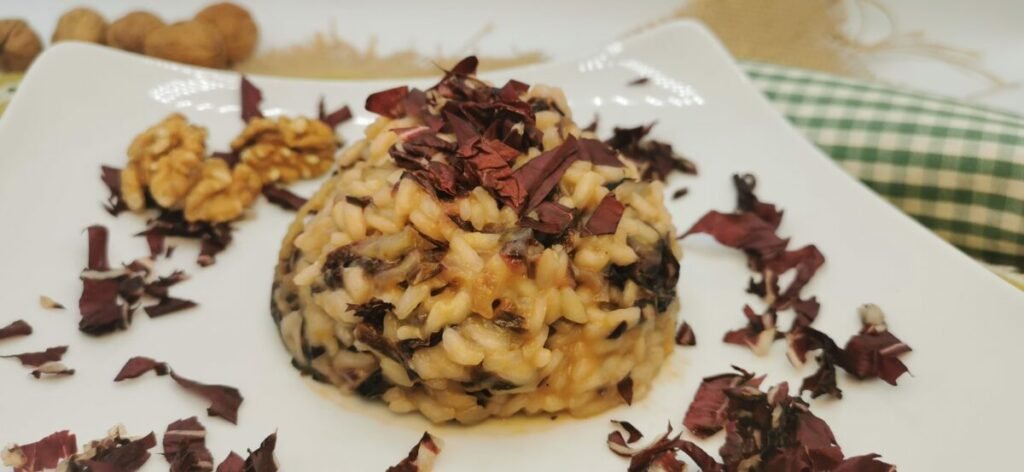 Arroz cremoso de tono rojizo con trozos tiernos de achicoria y queso parmesano para Risotto de Achicoria