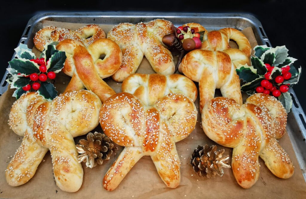 Panecillos horneados en forma de lazo con corteza dorada y semillas de sésamo para Lazos Navideños