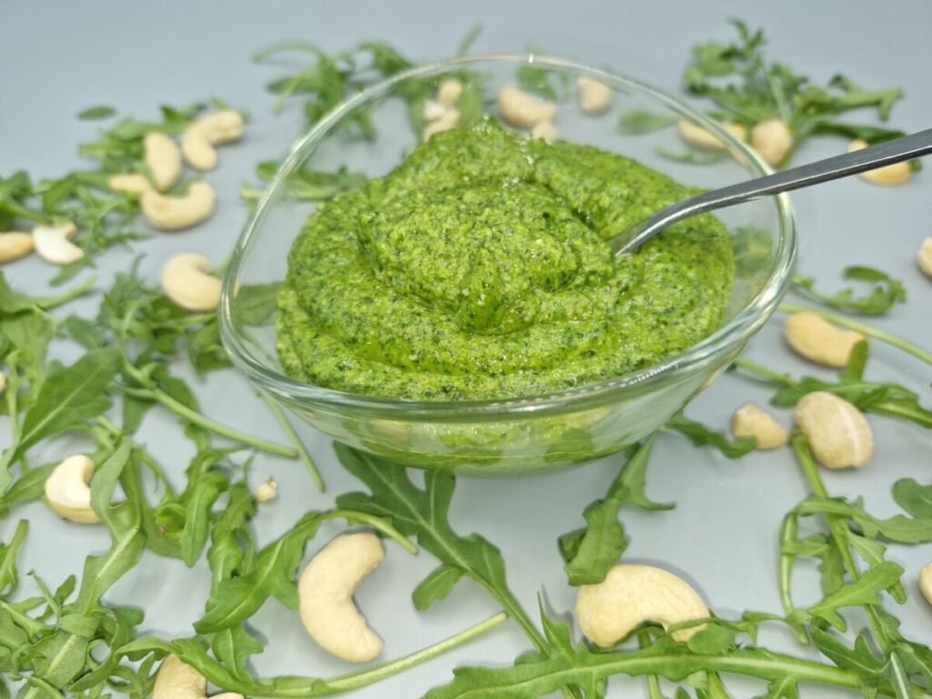 Salsa verde vibrante y cremosa con textura de frutos secos triturados para Pesto de Rúcula fresco